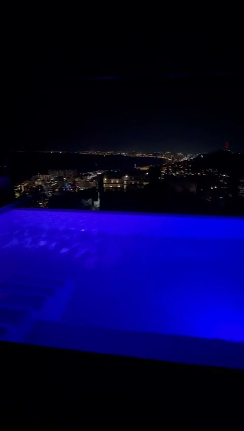 Borde infinito iluminado de noche frente a la bahía