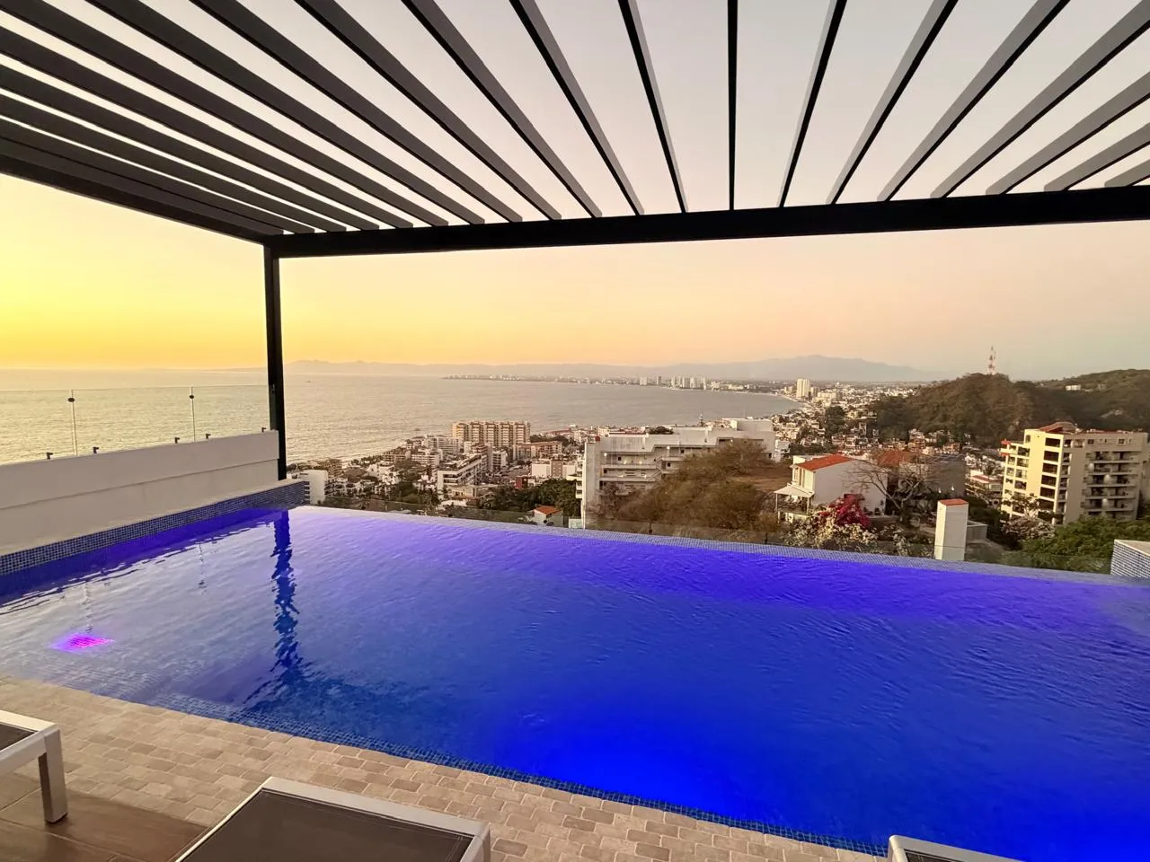 Alberca infinita bajo la pérgola al atardecer