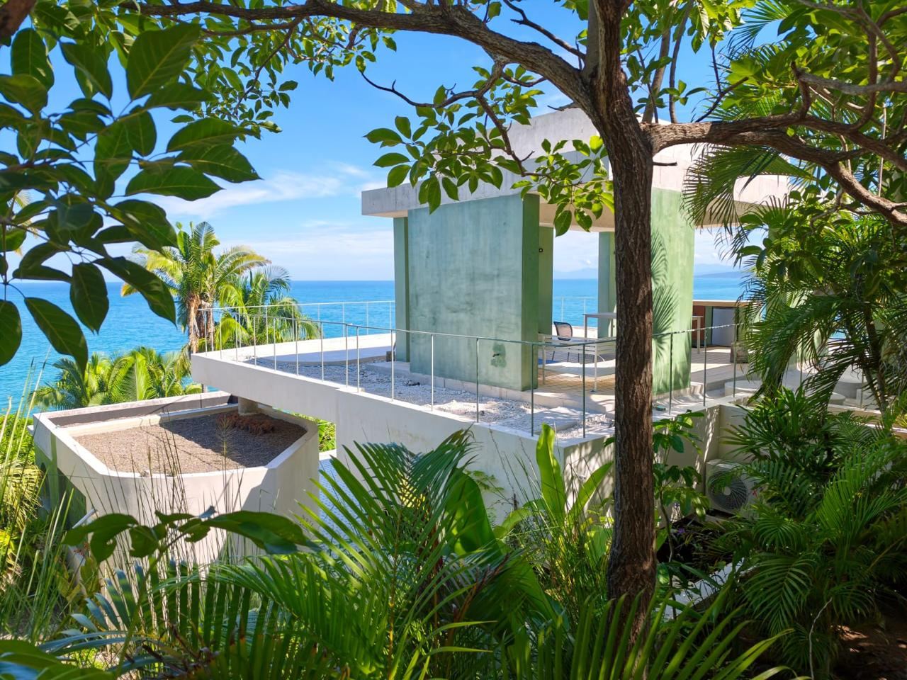 Casa de concreto verde entre la selva frente al mar