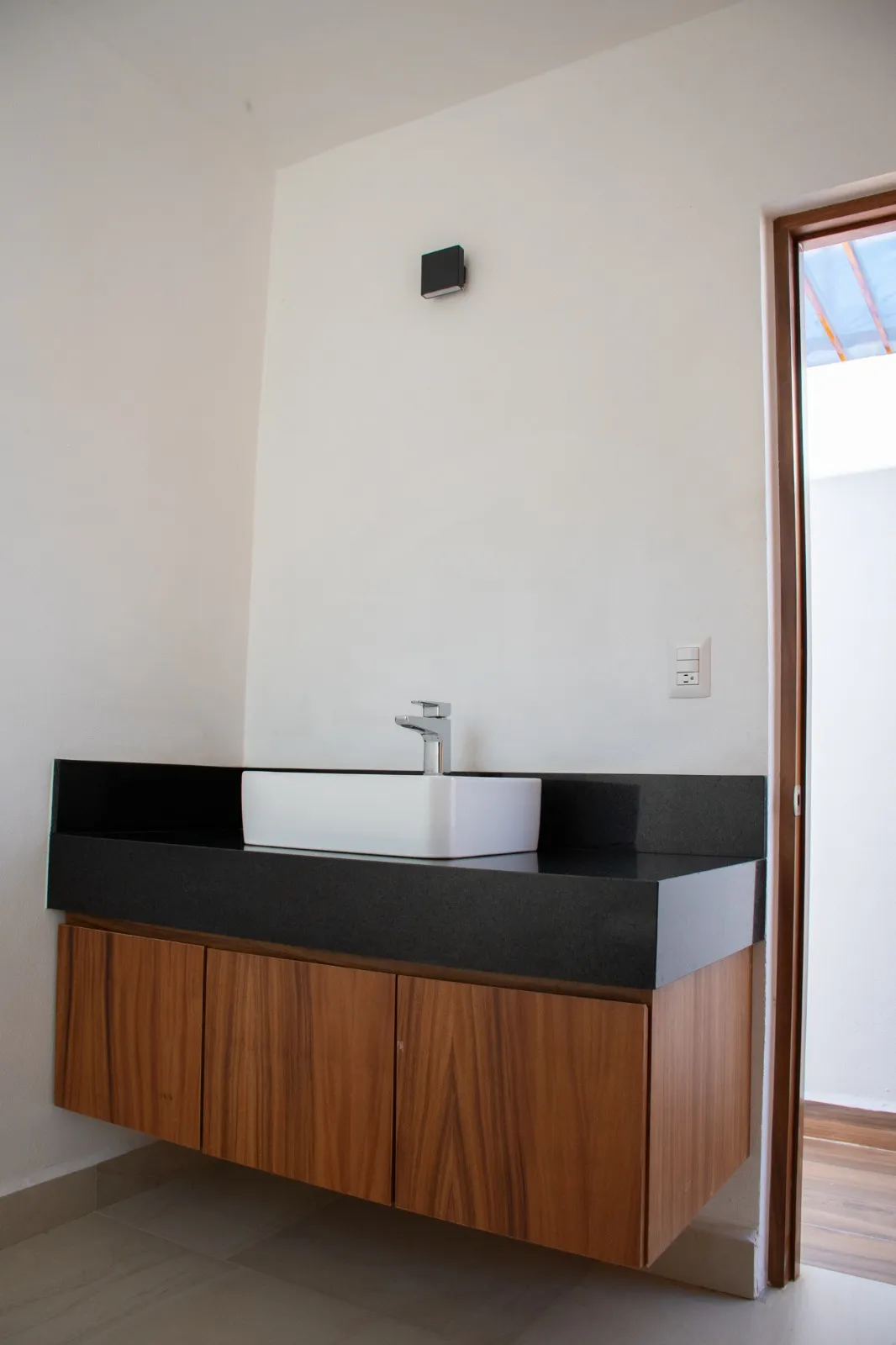 Baño con mueble de madera y cubierta negra